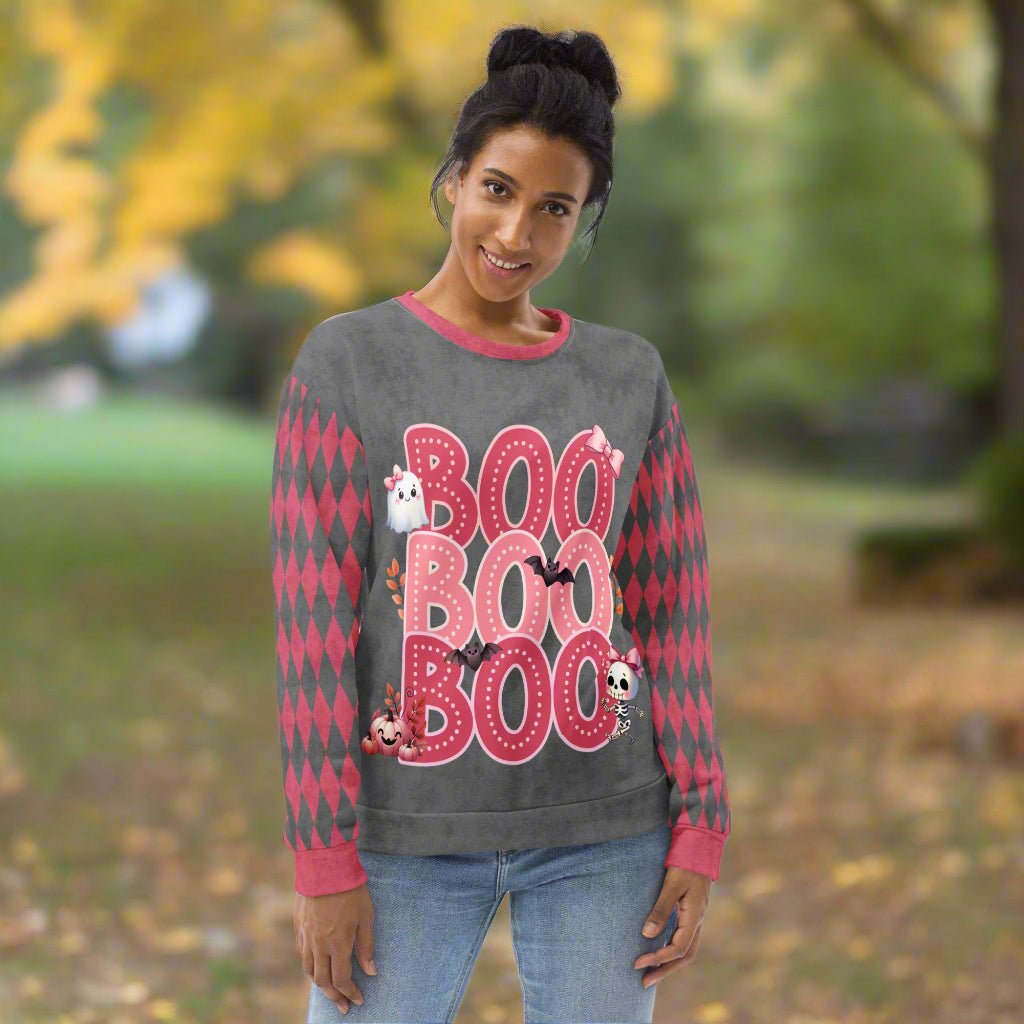 Woman wearing a Halloween-themed sweater with 'BOO' text and ghost graphics outdoors.