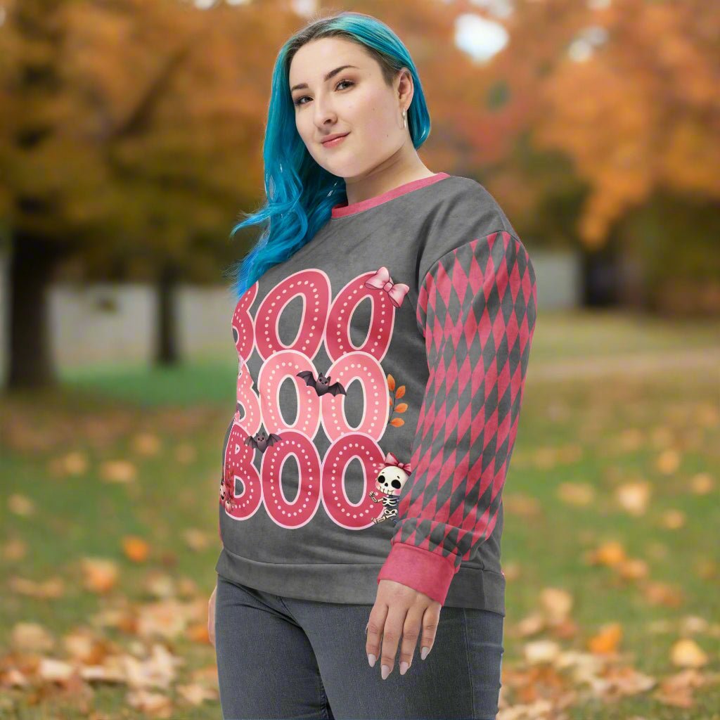 Person wearing a gray and pink 'BOO' Halloween-themed sweater outdoors