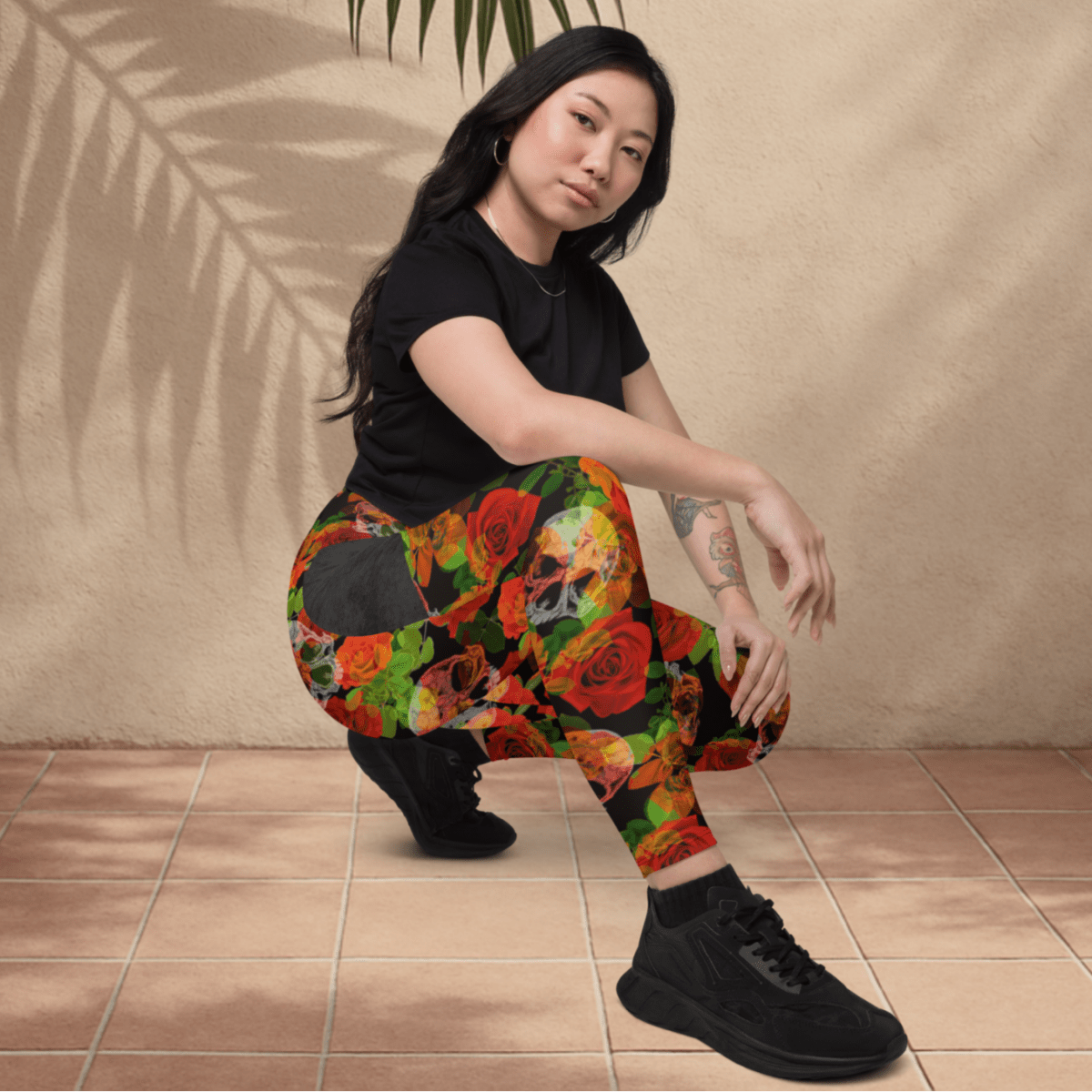 Person wearing colorful floral skull pants sitting on a tiled floor.