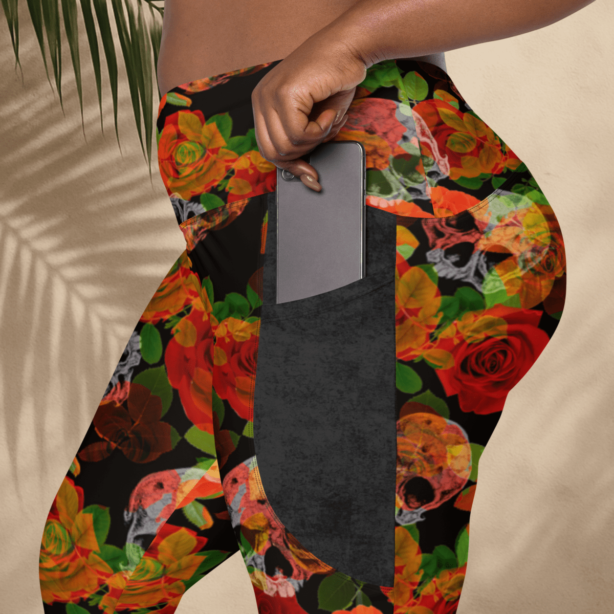 Colorful floral and skull patterned leggings with a pocket on a neutral background