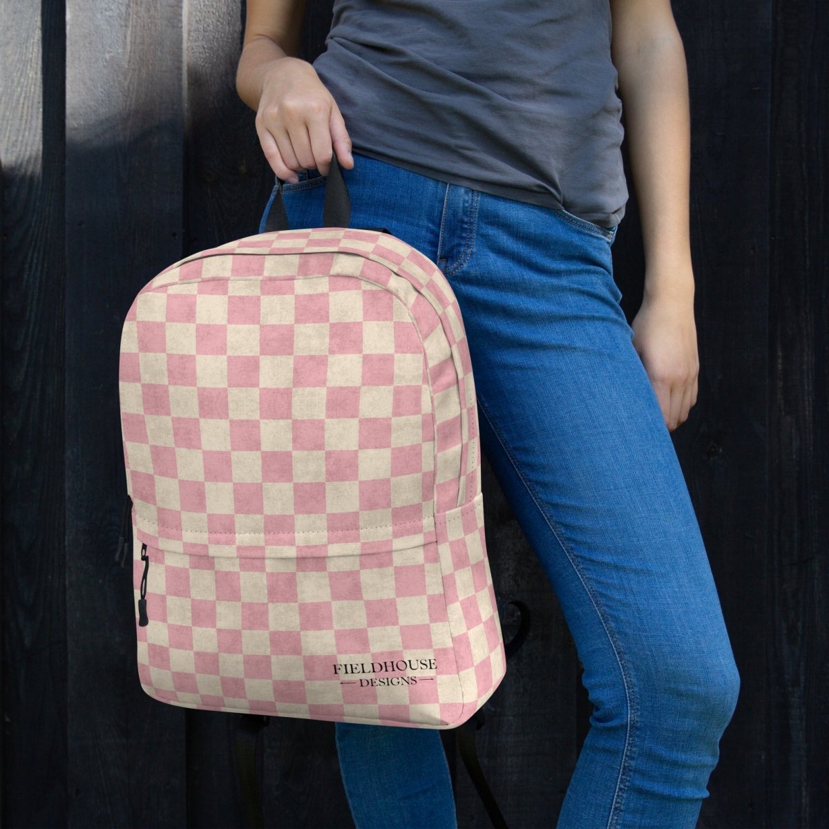Person holding a pink and white checkered backpack with 'Fieldhouse Designs' branding.