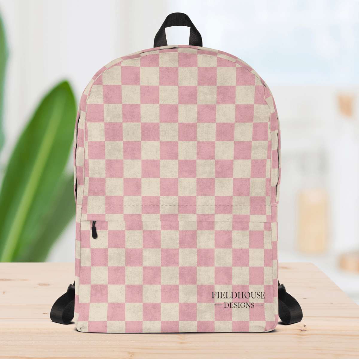 Pink and beige checkered backpack with 'Fieldhouse Designs' logo on a wooden surface.