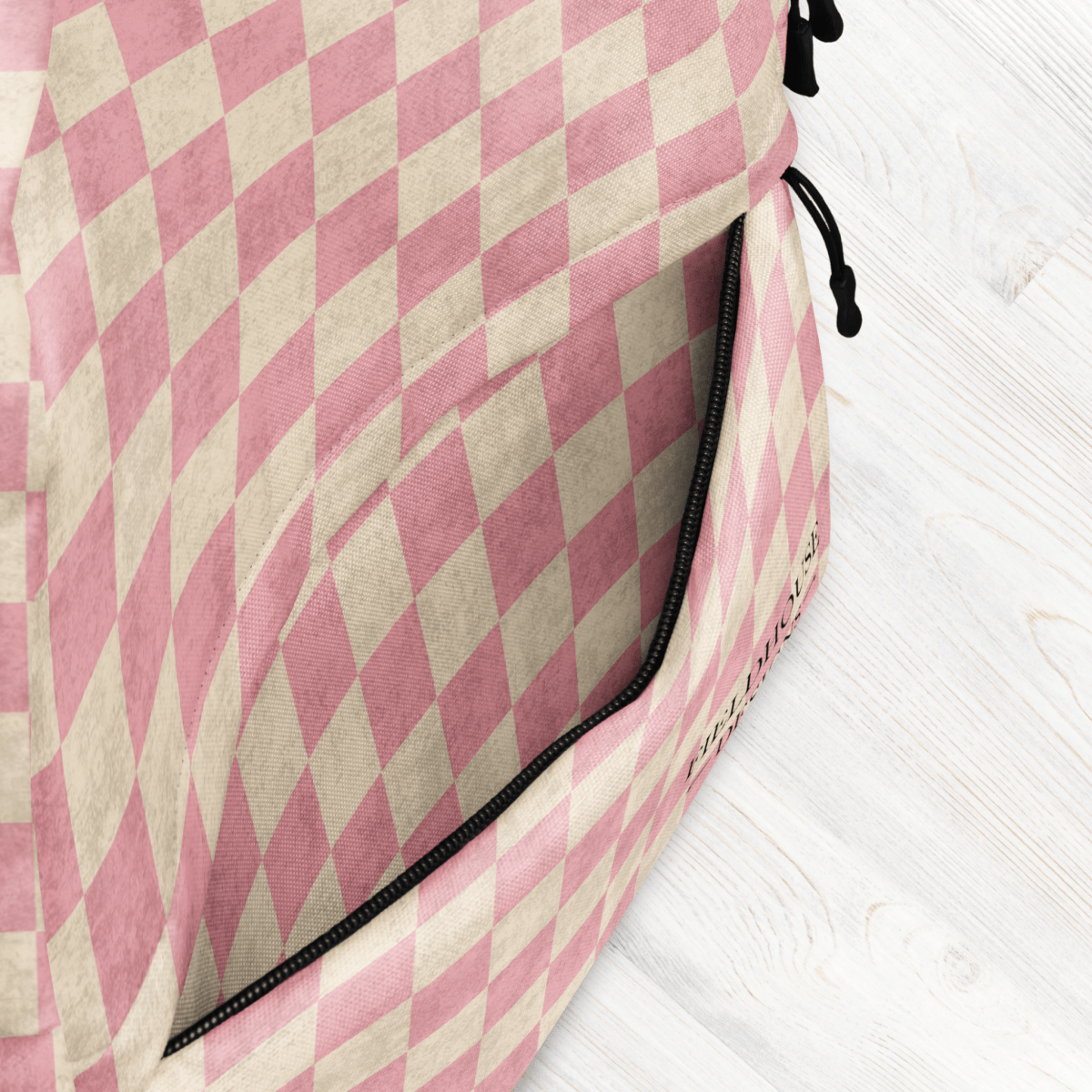 Pink and beige checkered bag on a white wooden surface showcasing the outside pocket.