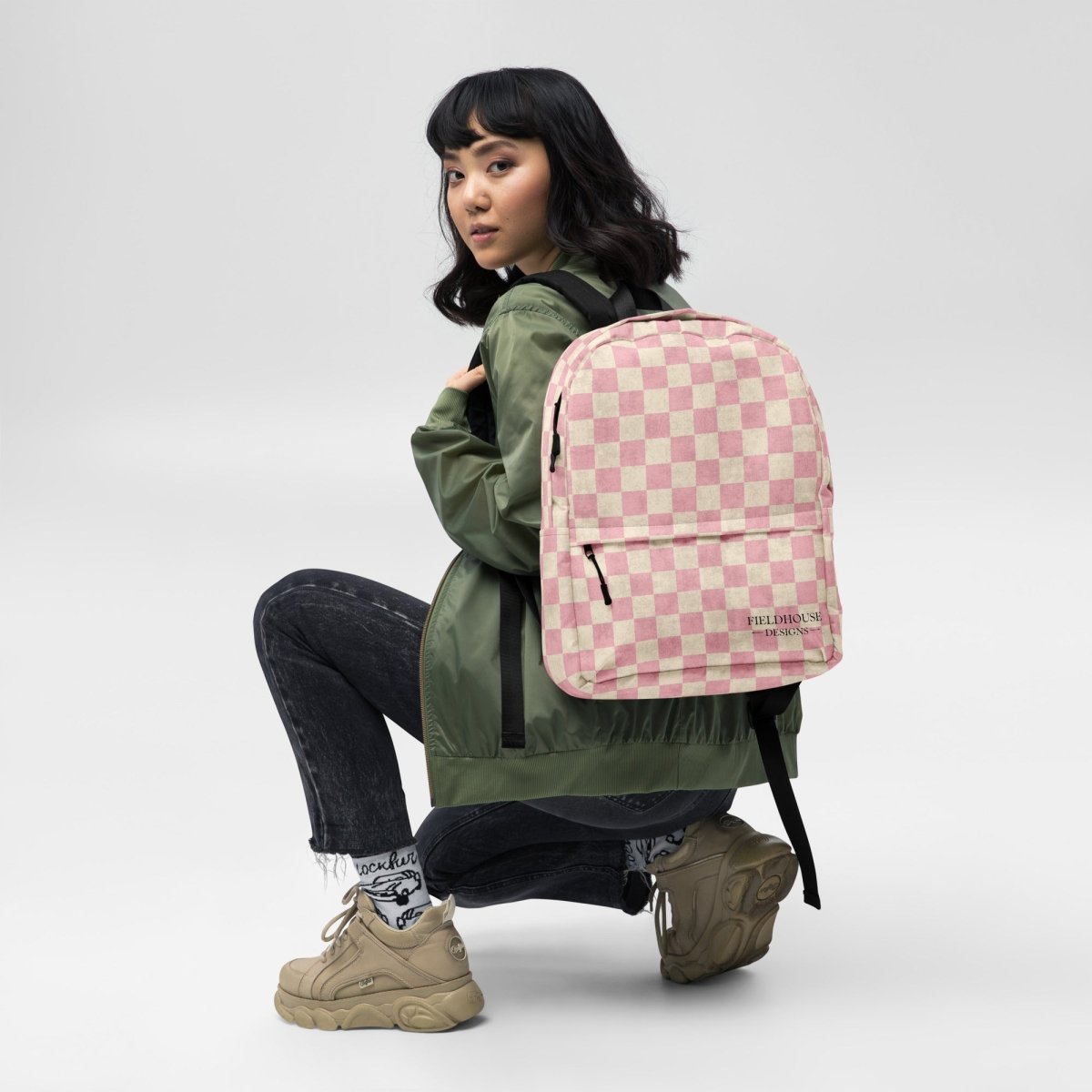 Person wearing a pink checkered backpack on a white background