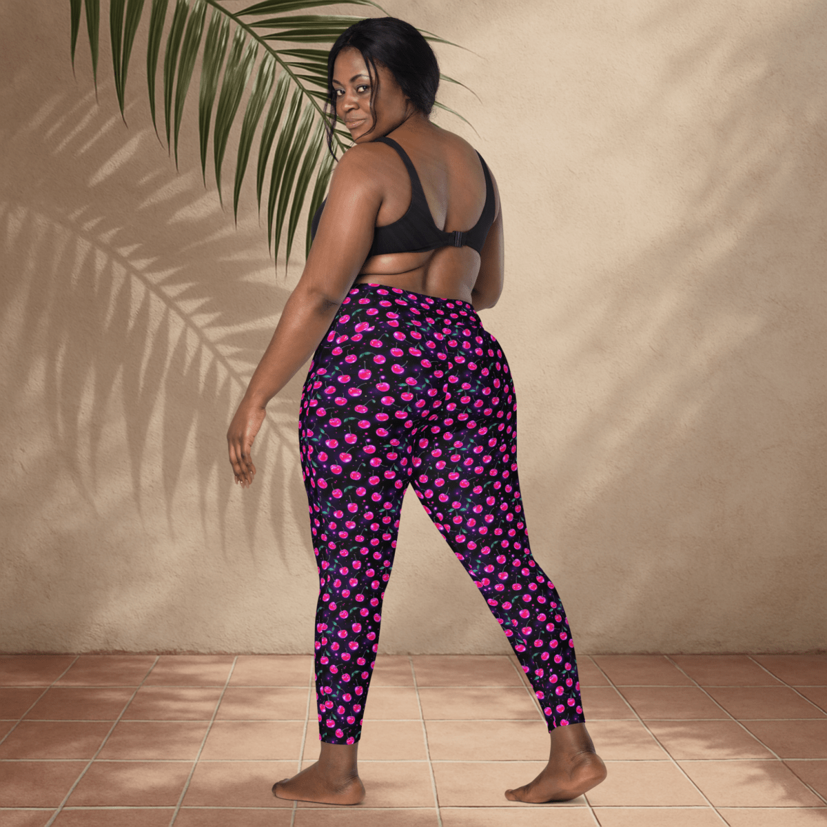 Woman wearing pink and black patterned leggings against a beige wall.