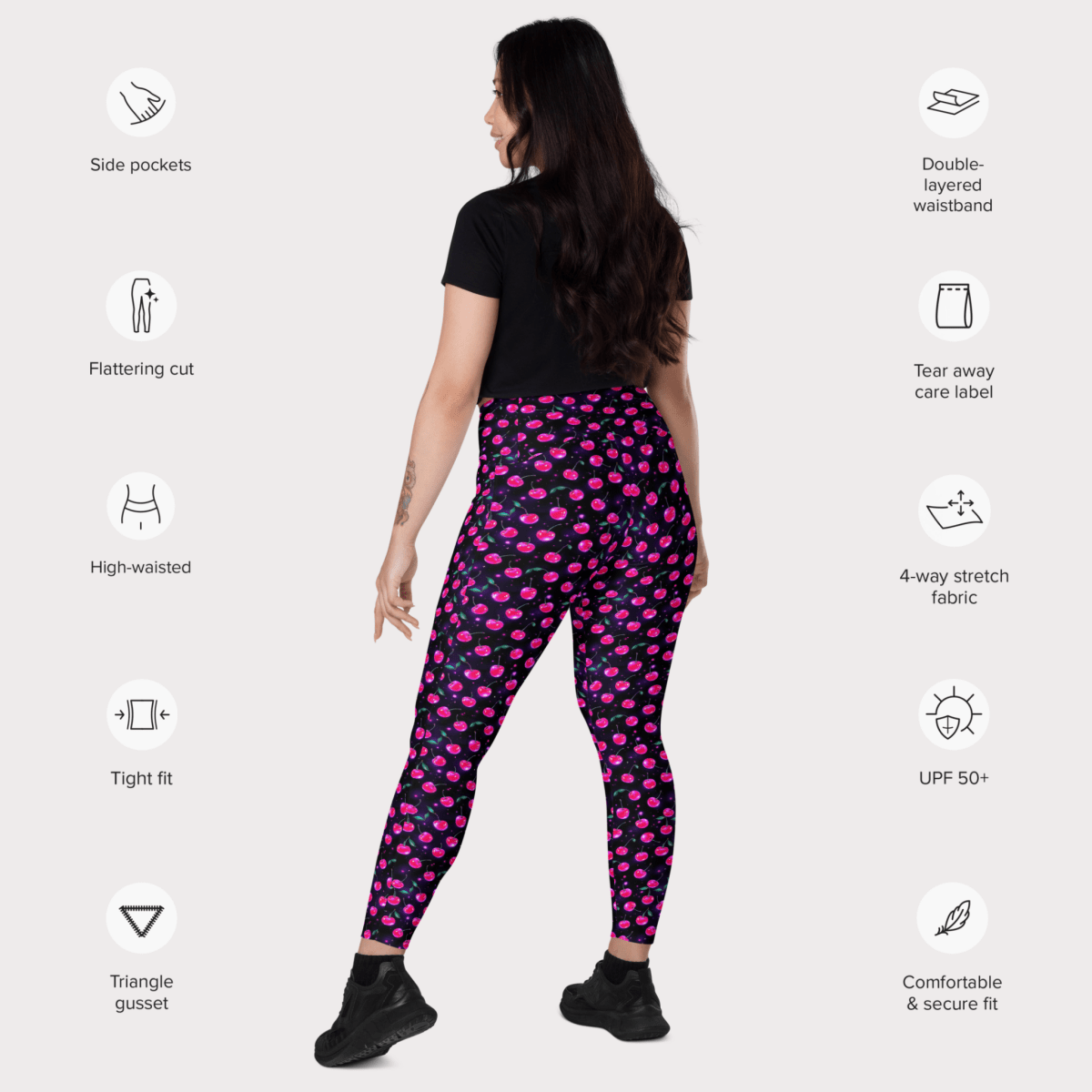 Woman wearing pink cherry print on black leggings with feature icons on a white background