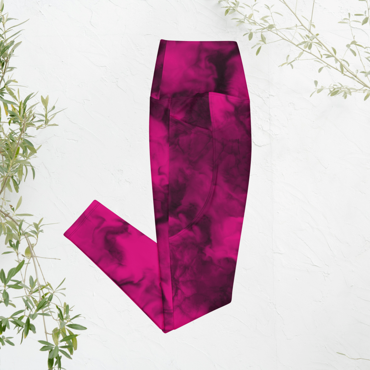 Pink tie-dye leggings on a white background with green leaves.