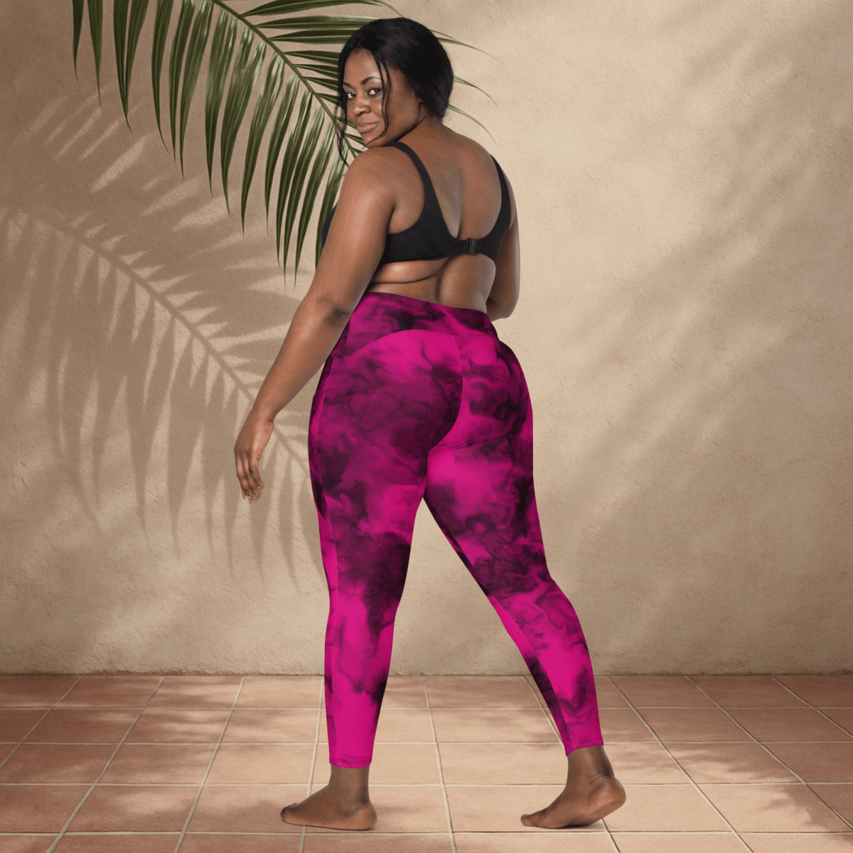 Person wearing pink and black tie-dye leggings standing against a beige wall.