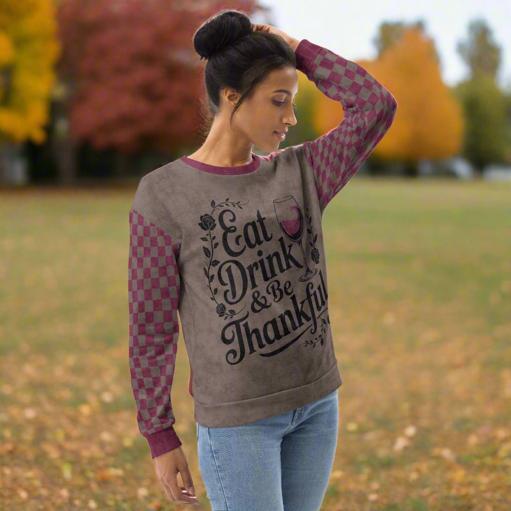 Woman wearing a sweater with 'Eat Drink & Be Thankful' text outdoors