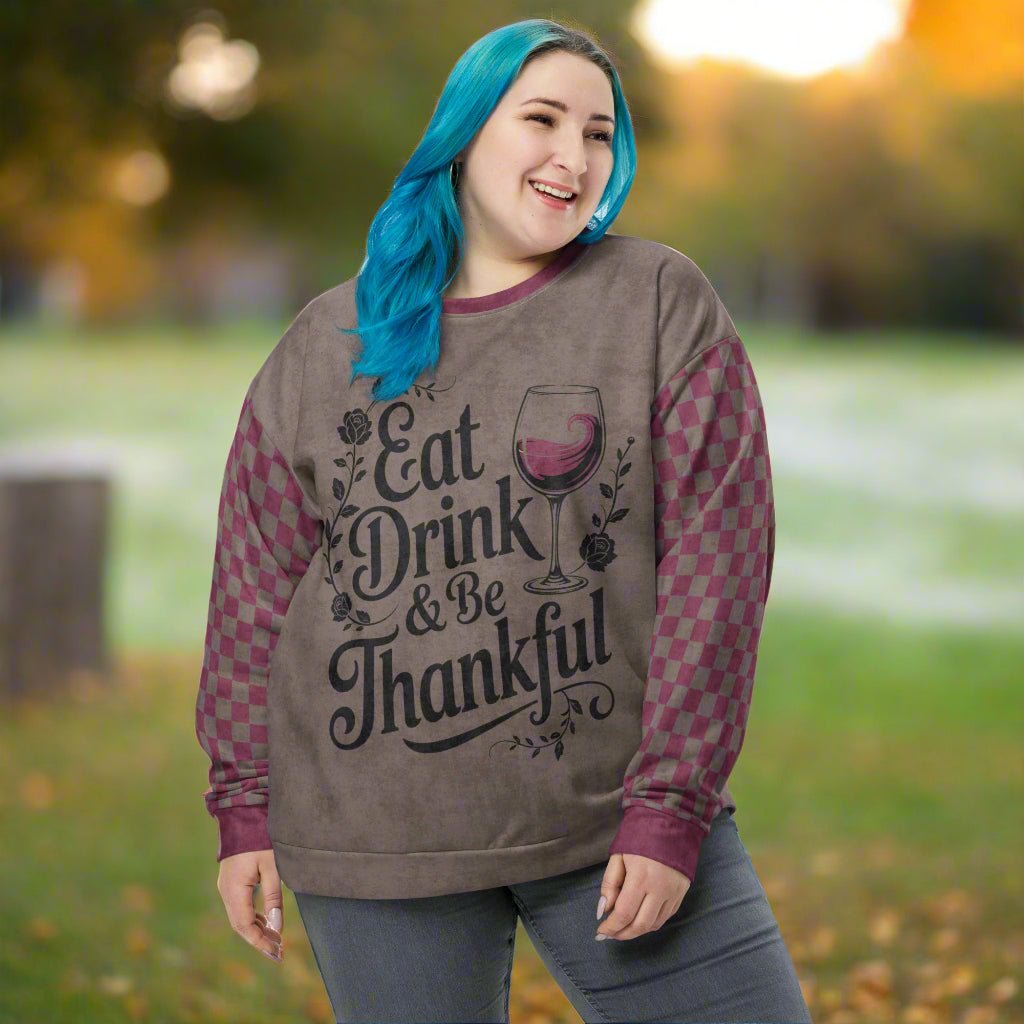 Person wearing a sweater with 'Eat Drink & Be Thankful' text in an outdoor setting