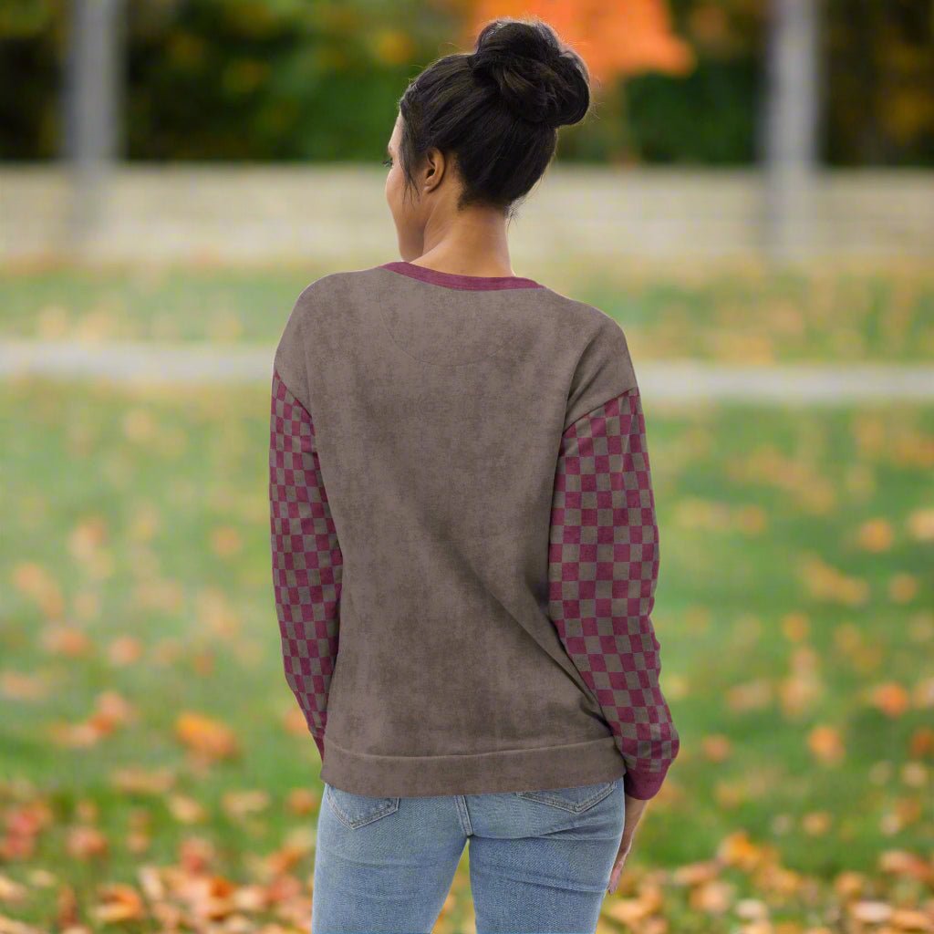 Person wearing an espresso sweatshirt with checkered sleeves outdoors