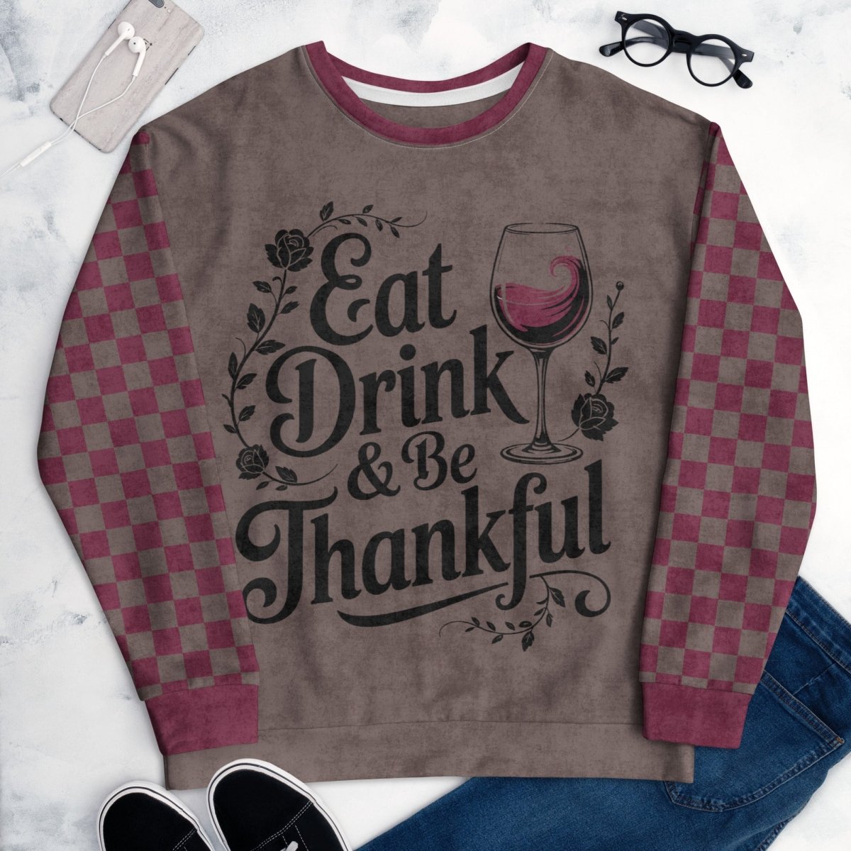 Sweatshirt with 'Eat Drink & Be Thankful' text and wine glass design on a marble surface.
