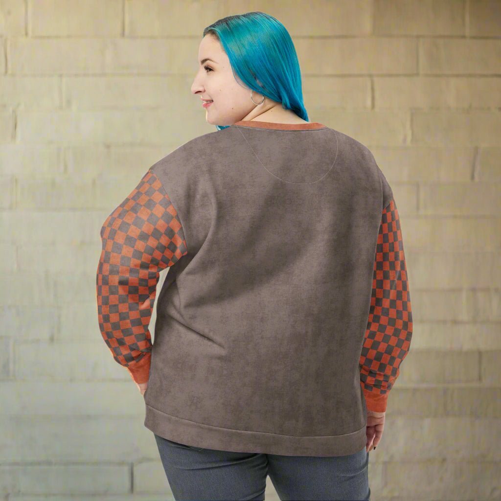 Person wearing a brown sweatshirt with checkered sleeves on a neutral background