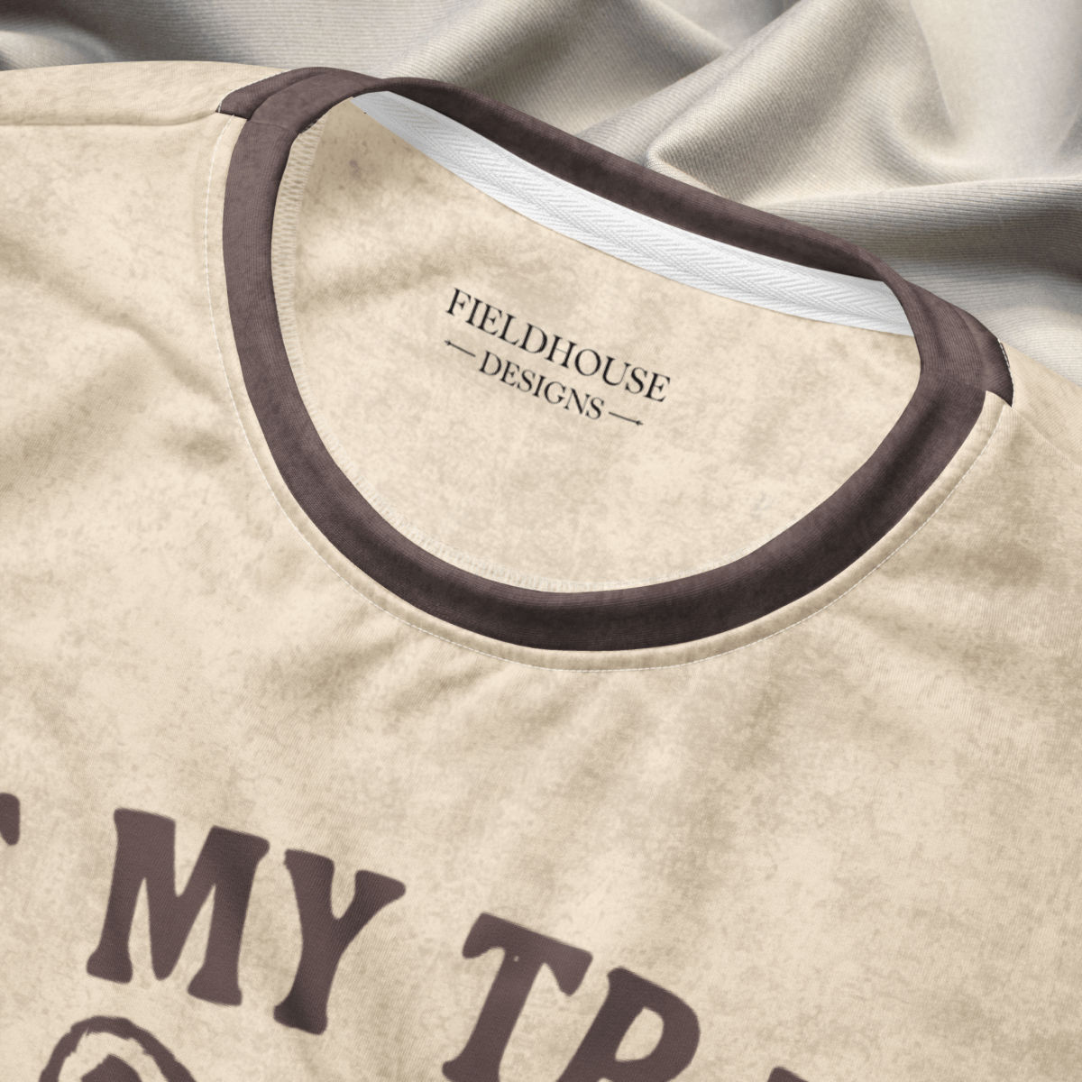 collar close up of Beige crewneck sweatshirt with espresso checkered sleeves. Featuring a raccoon reading a book graphic and text 'Not my trash, not my dumpster'