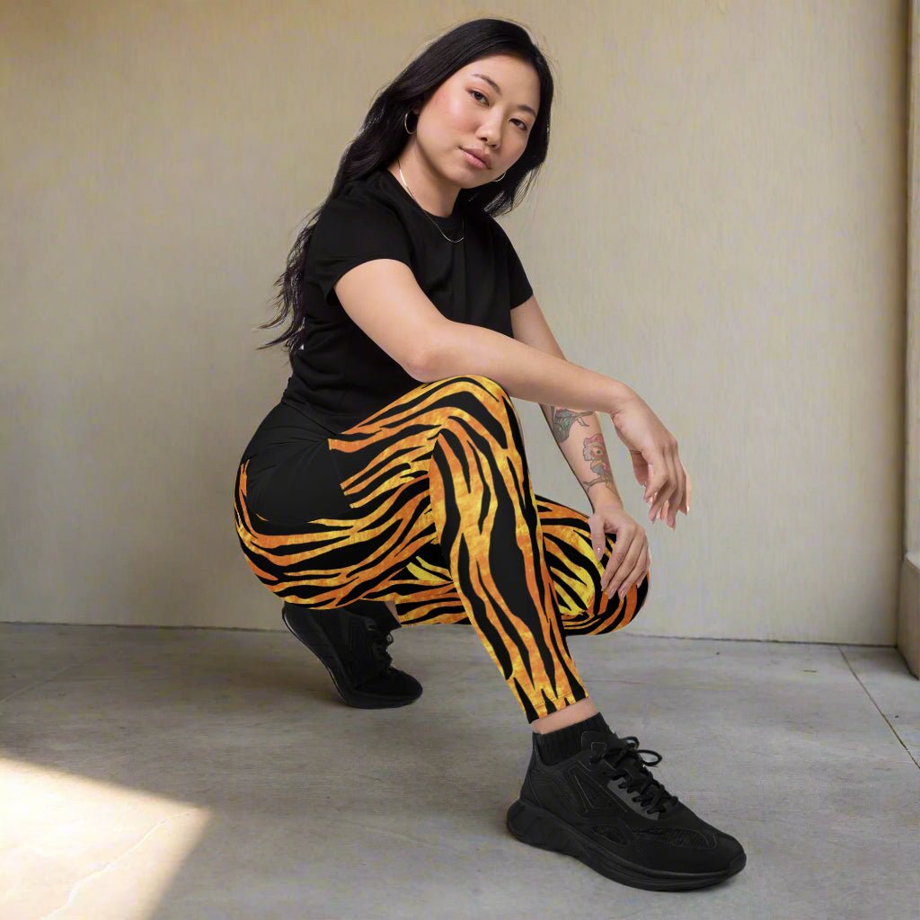Person wearing black and orange tiger stripe leggings on a neutral background