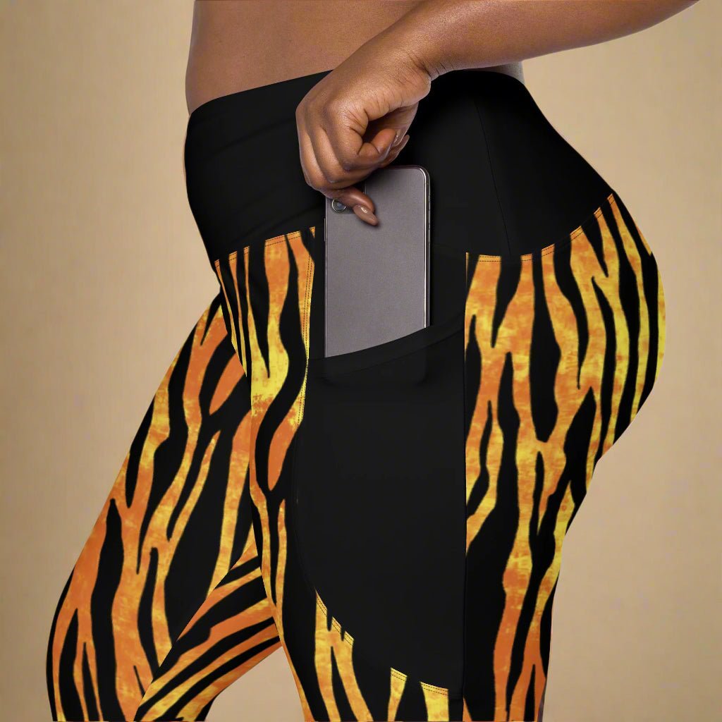 Black leggings with orange tiger stripe pattern worn by a person holding a phone.