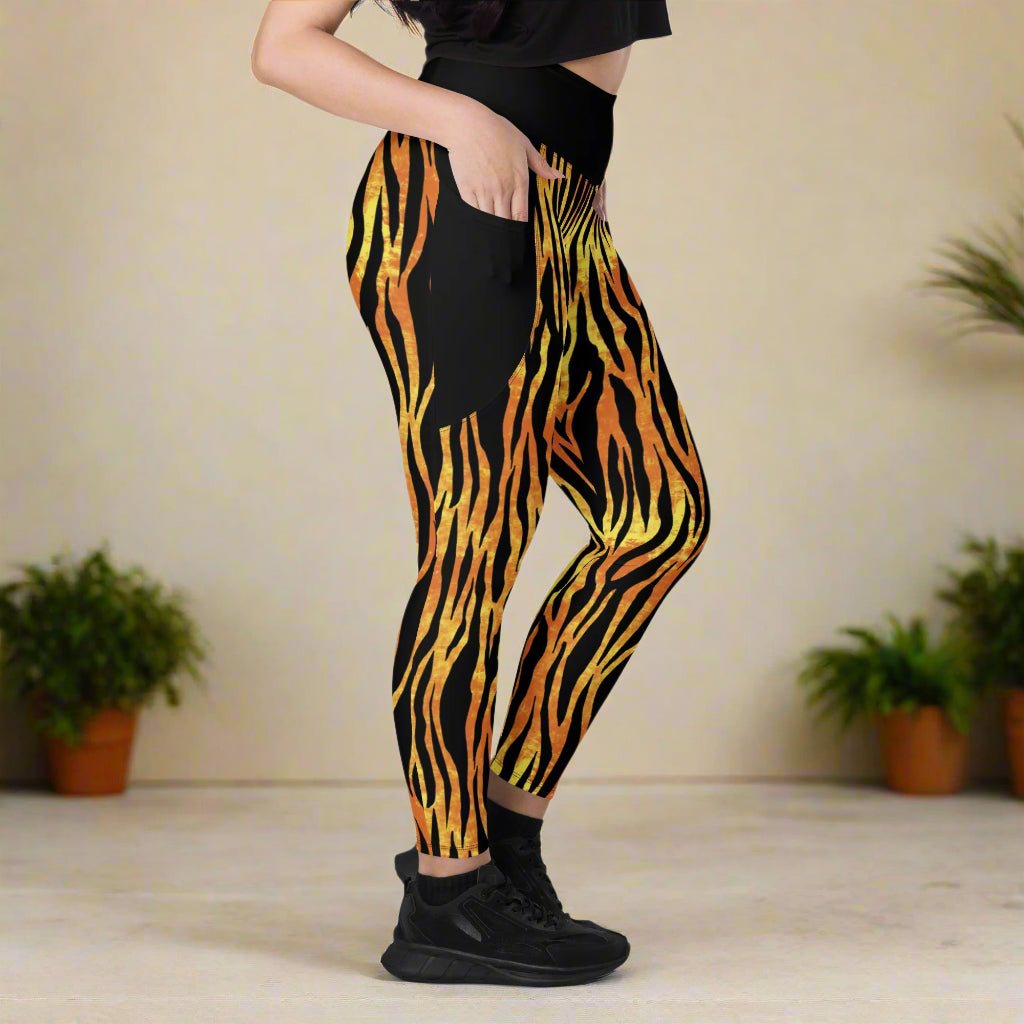Person wearing black leggings with orange and yellow tiger stripe pattern on a neutral background