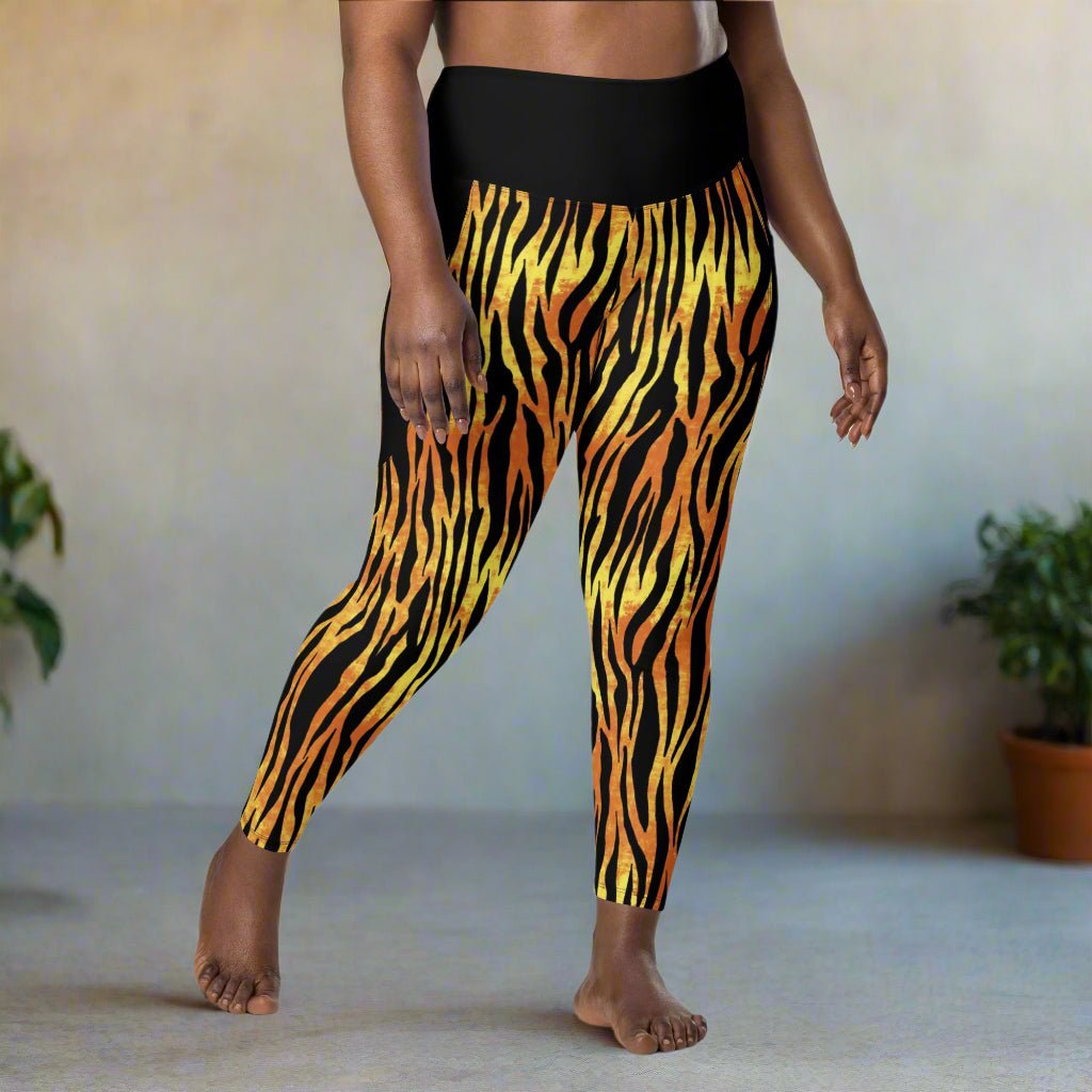 Black leggings with orange and yellow tiger stripe pattern worn by a person on a neutral background