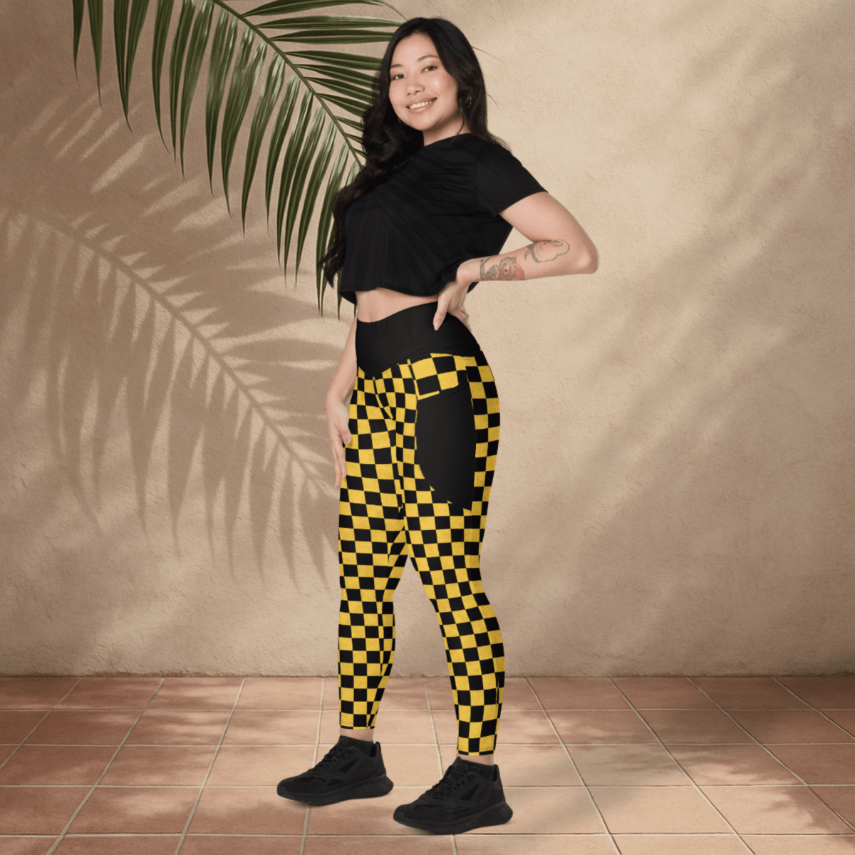 Woman wearing black and yellow checkered pants with a plain background