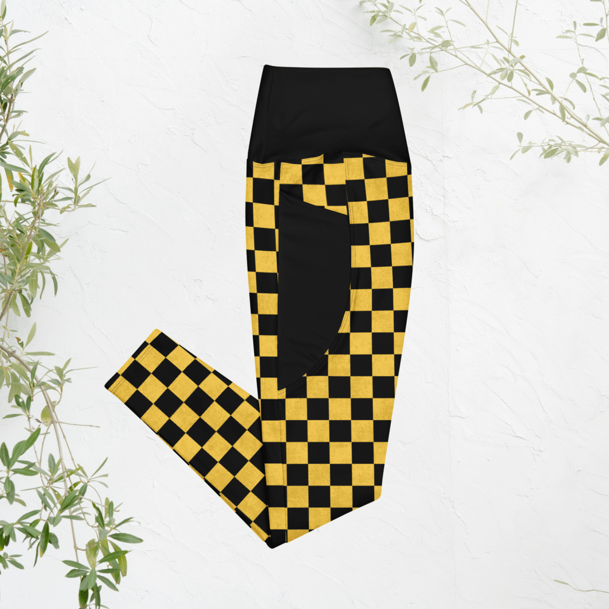 Black and yellow checkered leggings on a white background with green leaves.