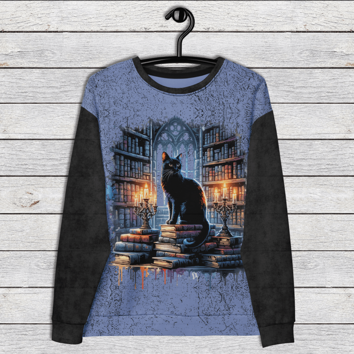 Sweatshirt with a cat on books design hanging on a wooden wall.