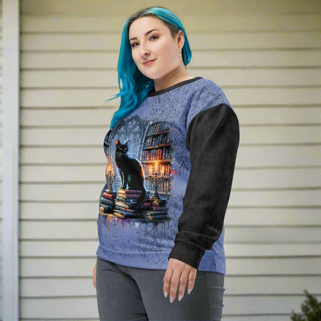 Person wearing a blue and black sweater with a cat and book design on a white background