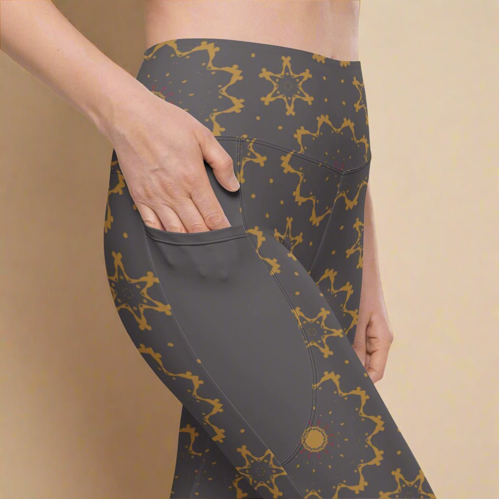 Dark gray leggings with gold star pattern worn by a person on a beige background
