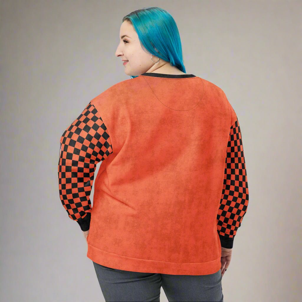 Person wearing an orange sweatshirt with checkered sleeves on a white background