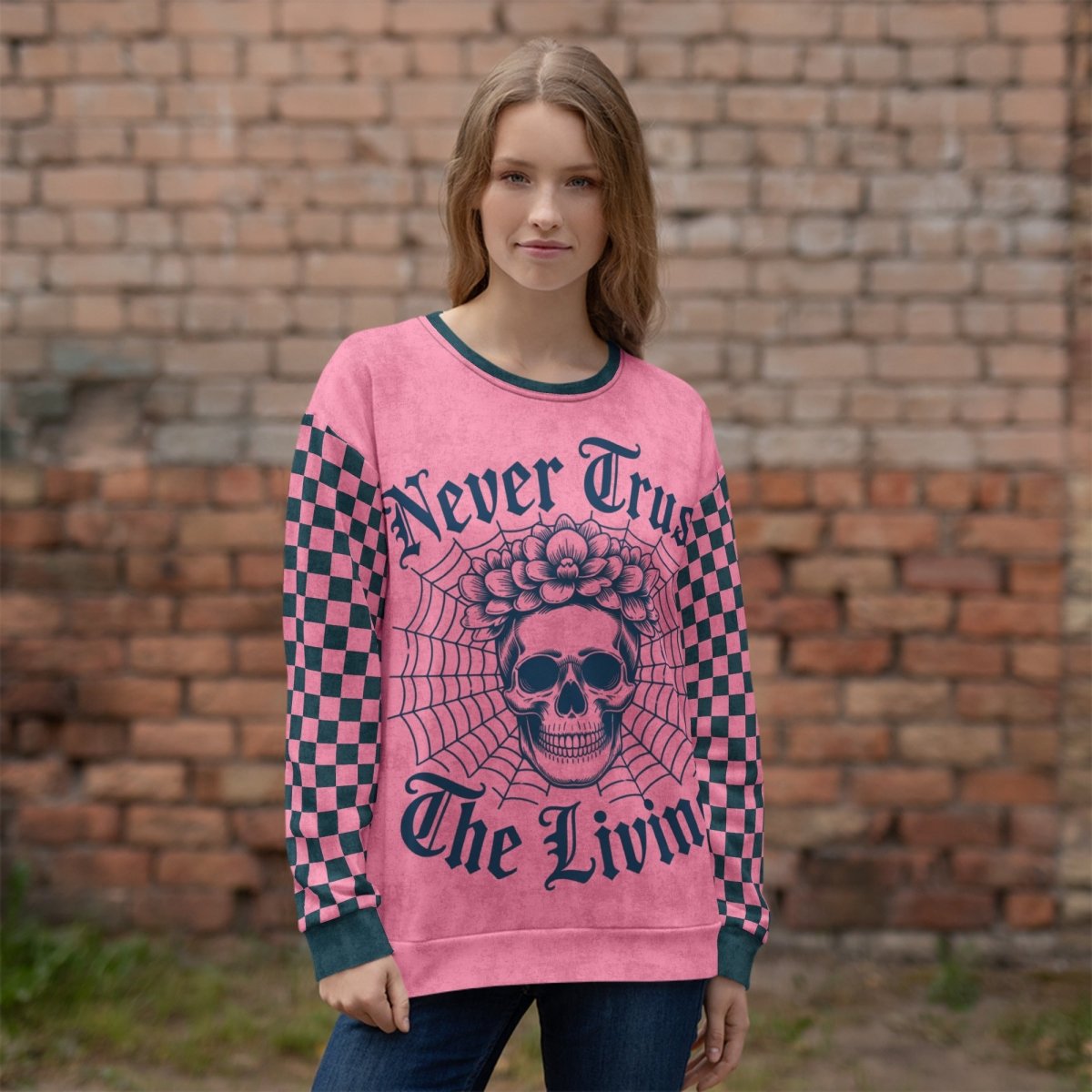 Person wearing a pink sweater with skull design and text in front of a brick wall