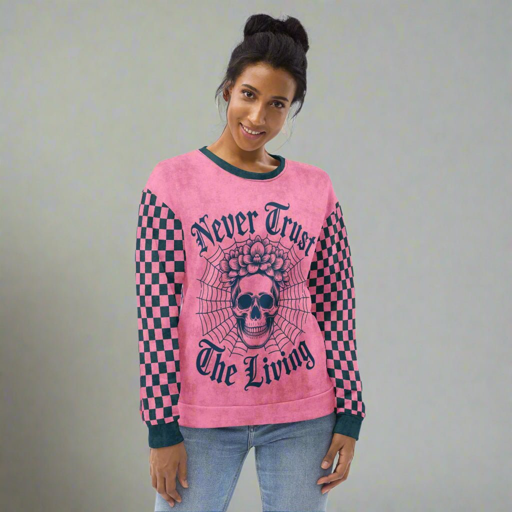 Person wearing a pink sweatshirt with skull design and text on a neutral background