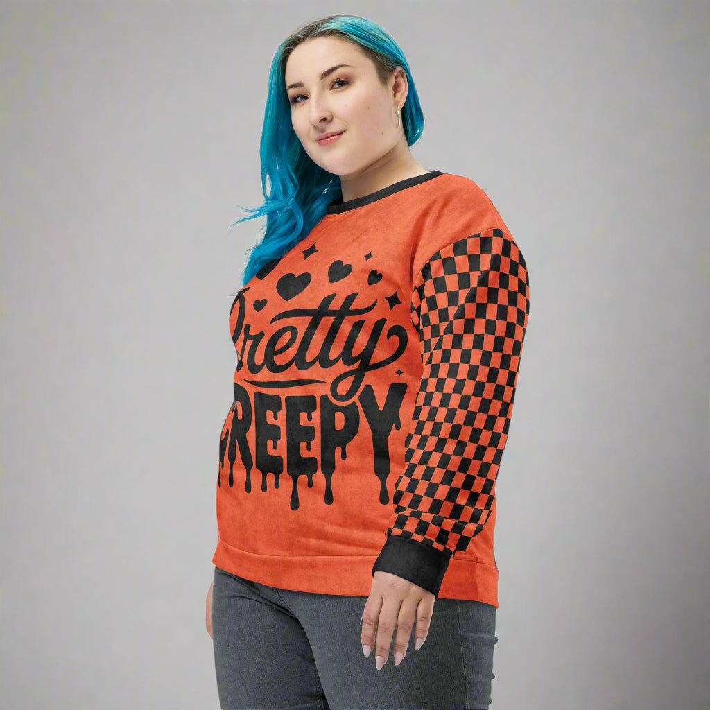 Person wearing an orange sweatshirt with black text and checkered sleeves on a neutral background