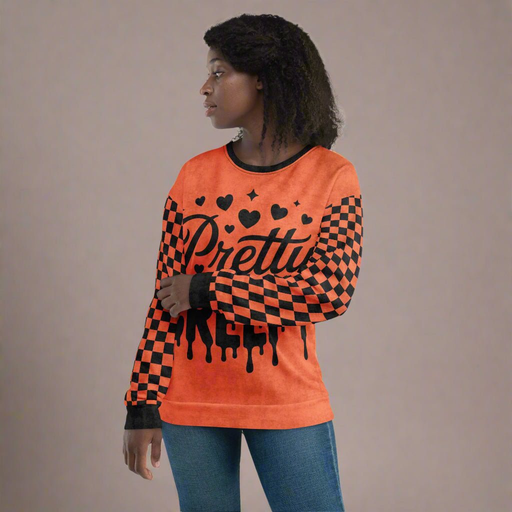 Person wearing an orange sweater with black checkered pattern and 'Pretty Creepy' text on a beige background