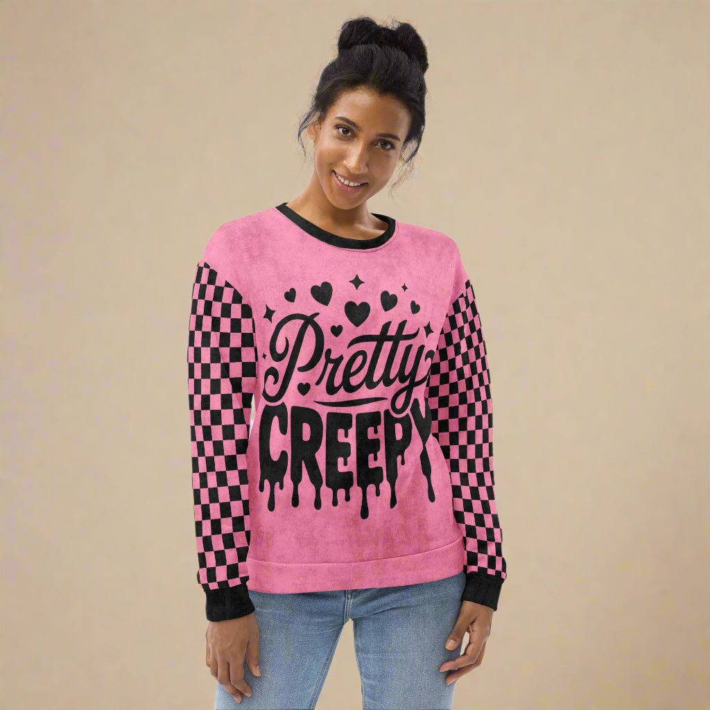 Person wearing a pink sweatshirt with 'Pretty Creepy' text and checkered pattern on a neutral background