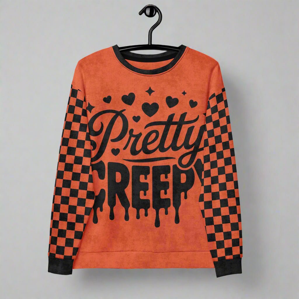 Orange sweatshirt with 'Pretty Creepy' text and checkered sleeves on a hanger