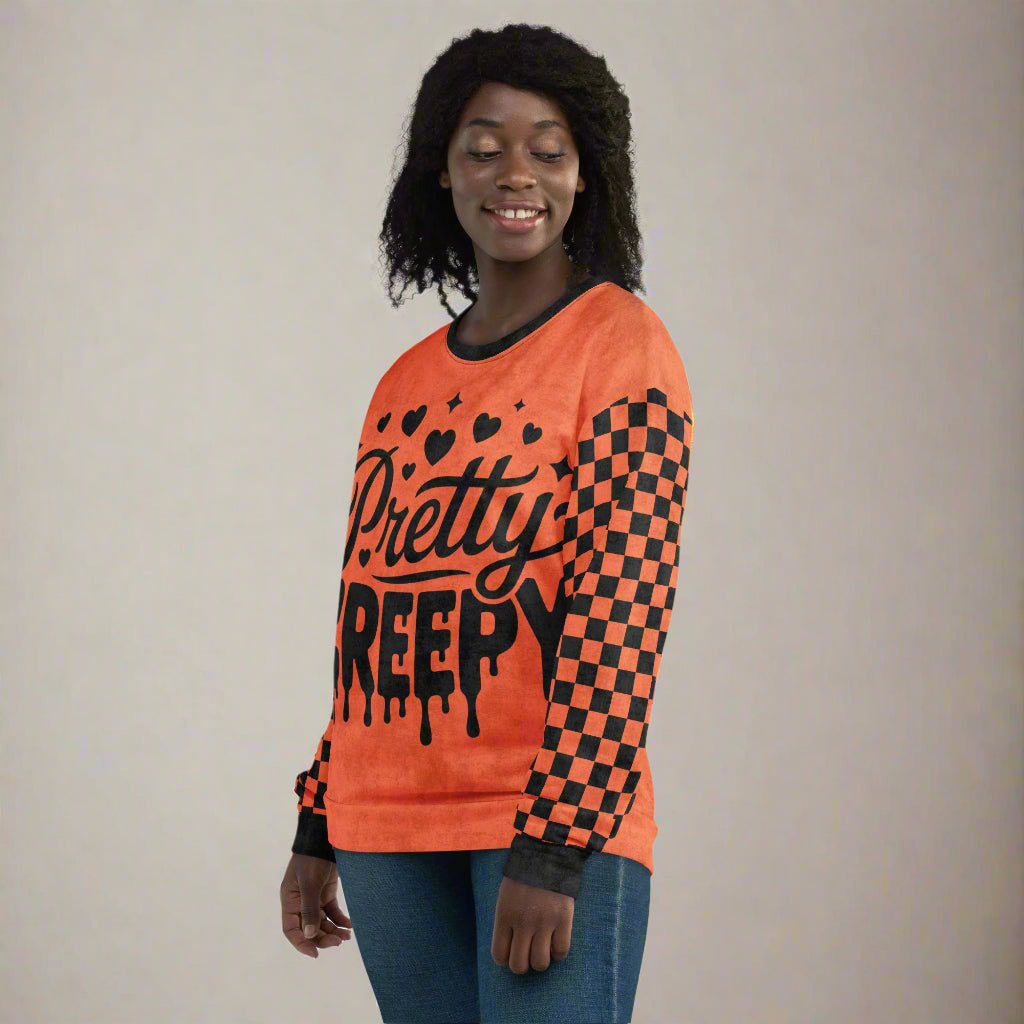 Person wearing an orange sweater with black text and checkered pattern on a plain background