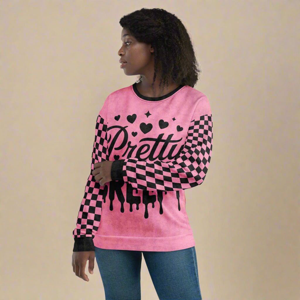 Person wearing a pink sweatshirt with black text and checkered sleeves on a white background