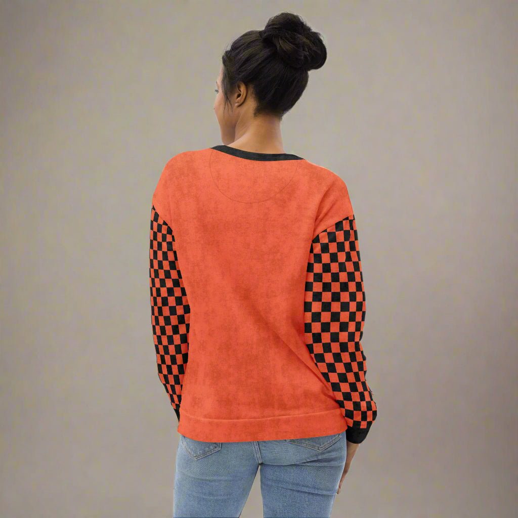 Person wearing an orange sweatshirt with checkered sleeves on a neutral background