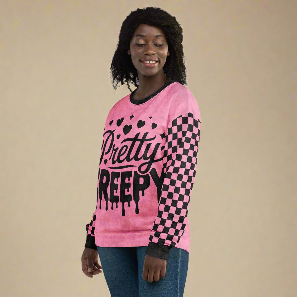 Person wearing a pink sweater with 'Pretty Creepy' text and black hearts on a white background