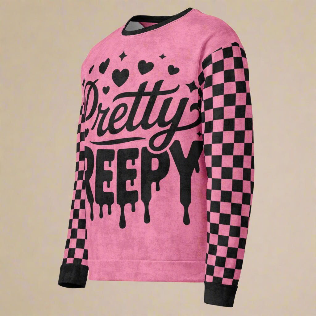 Pink sweatshirt with 'Pretty Creepy' text and black checkered sleeves on a beige background