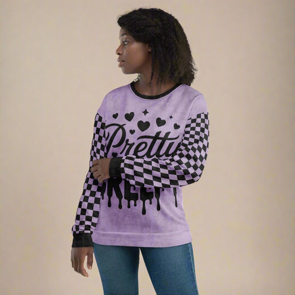 Person wearing a purple sweater with checkered sleeves and 'Pretty Creepy' text on a neutral background