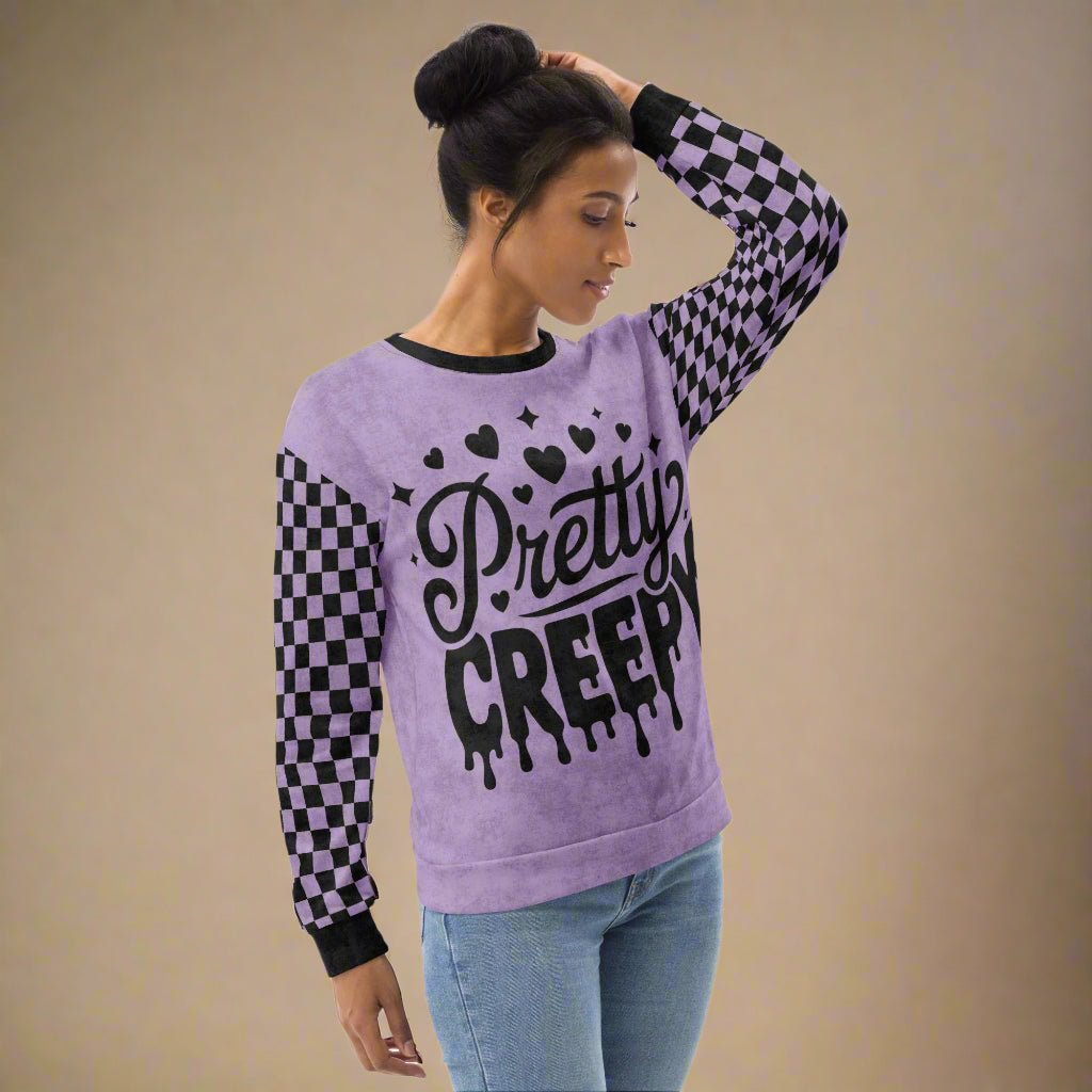 Woman wearing a purple sweater with 'Pretty Creepy' text and checkered sleeves on a beige background