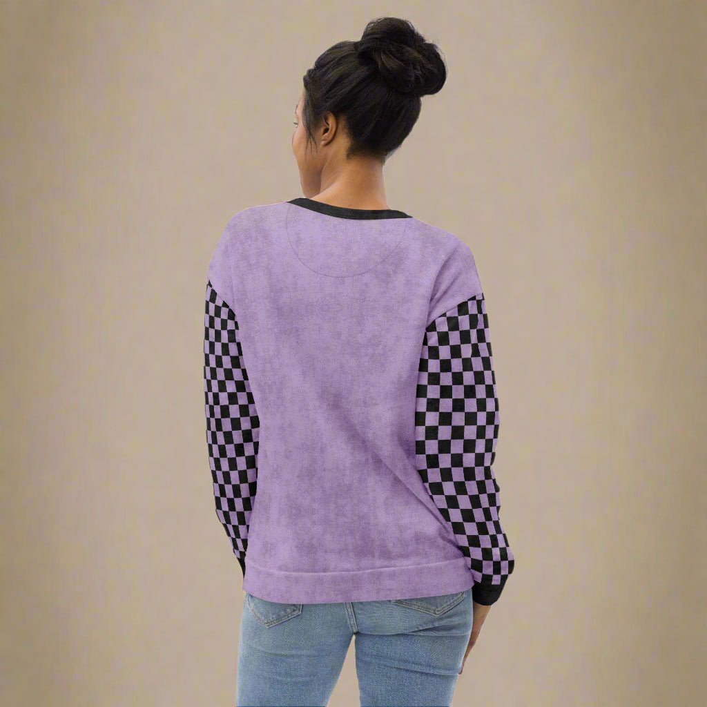 Person wearing a purple sweatshirt with checkered sleeves on a neutral background
