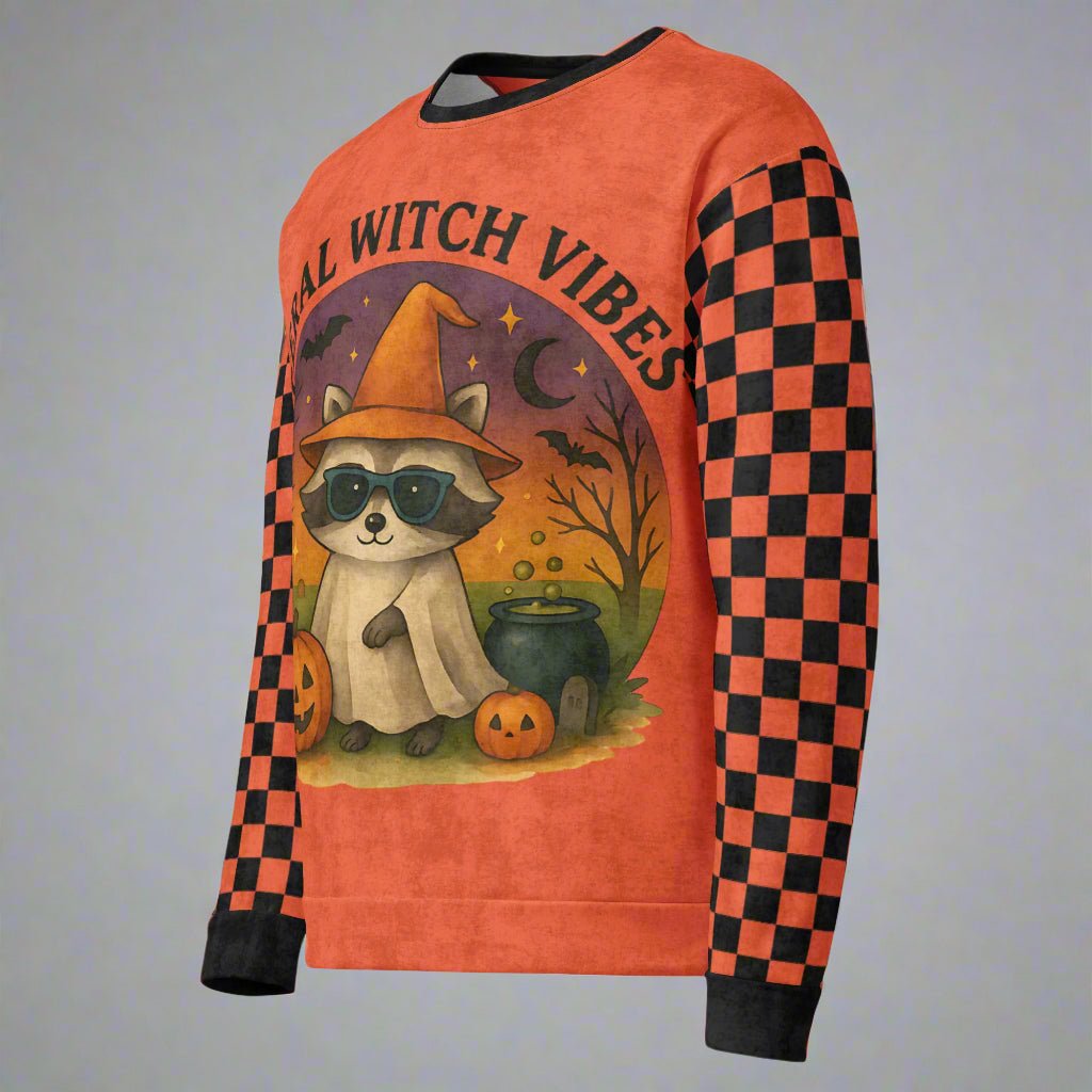 Sweatshirt with a raccoon wearing sunglasses and a witch hat, surrounded by Halloween elements on an orange background.
