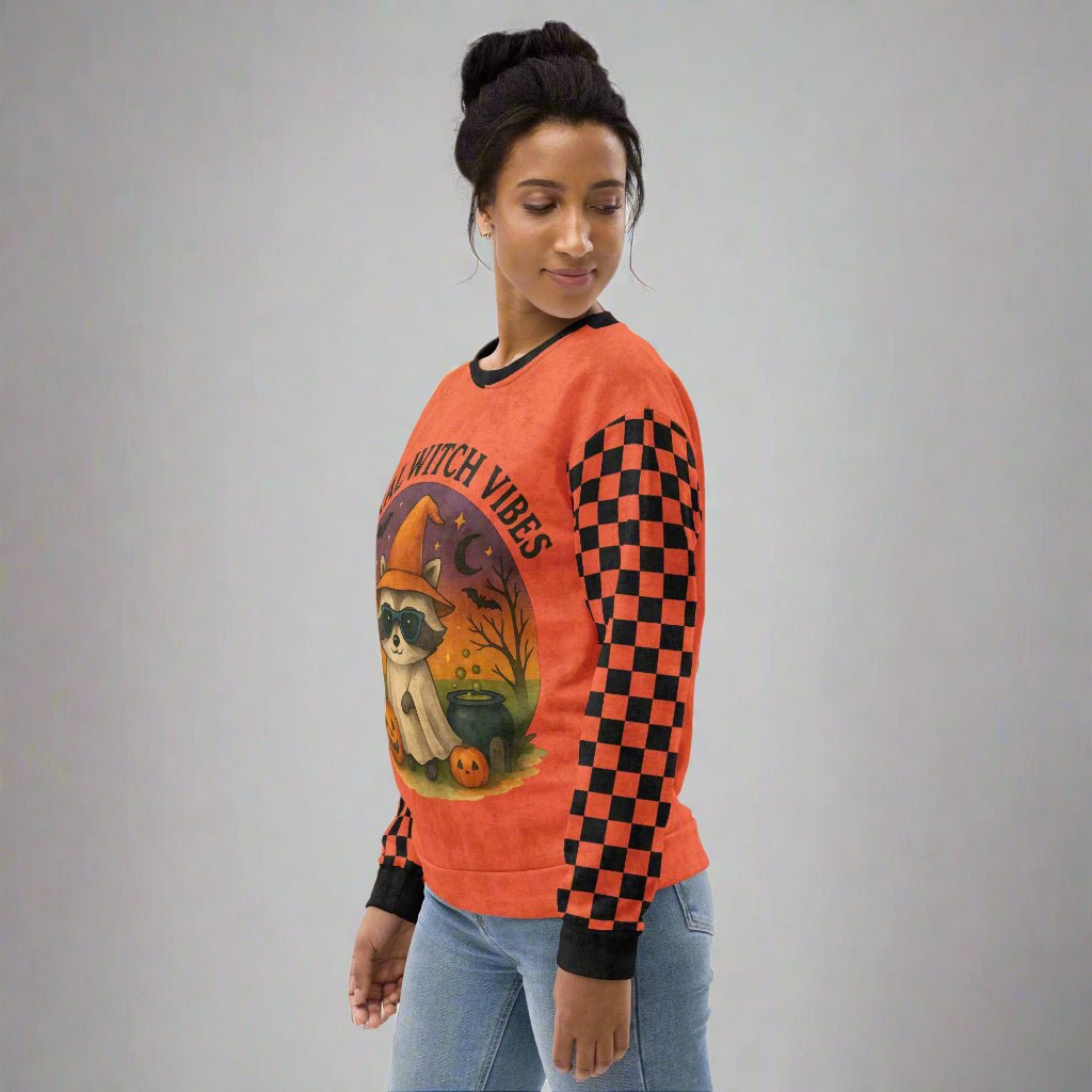 Woman wearing a Halloween-themed orange sweatshirt with checkered sleeves on a neutral background