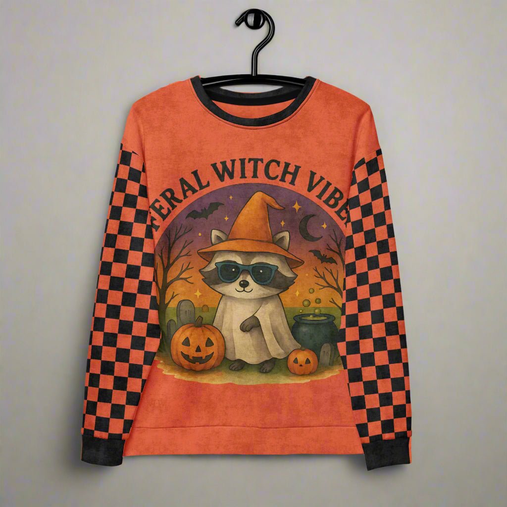 Halloween-themed sweatshirt with raccoon graphic and 'Feral Witch Vibes' text on a hanger.