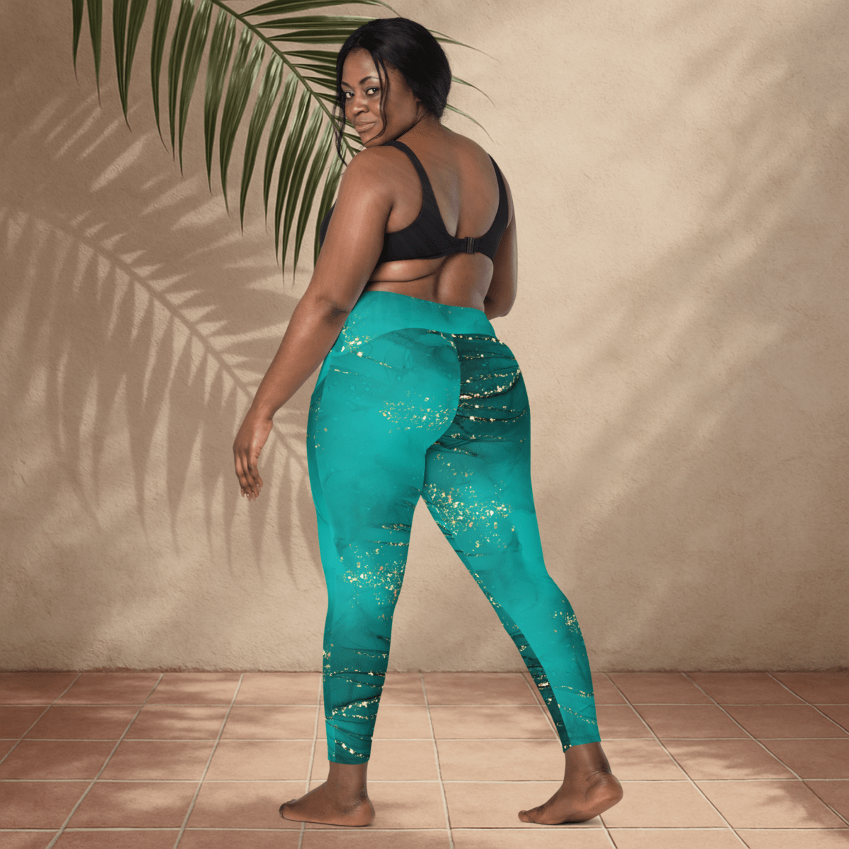 Woman wearing teal leggings with a subtle pattern, standing against a beige wall.