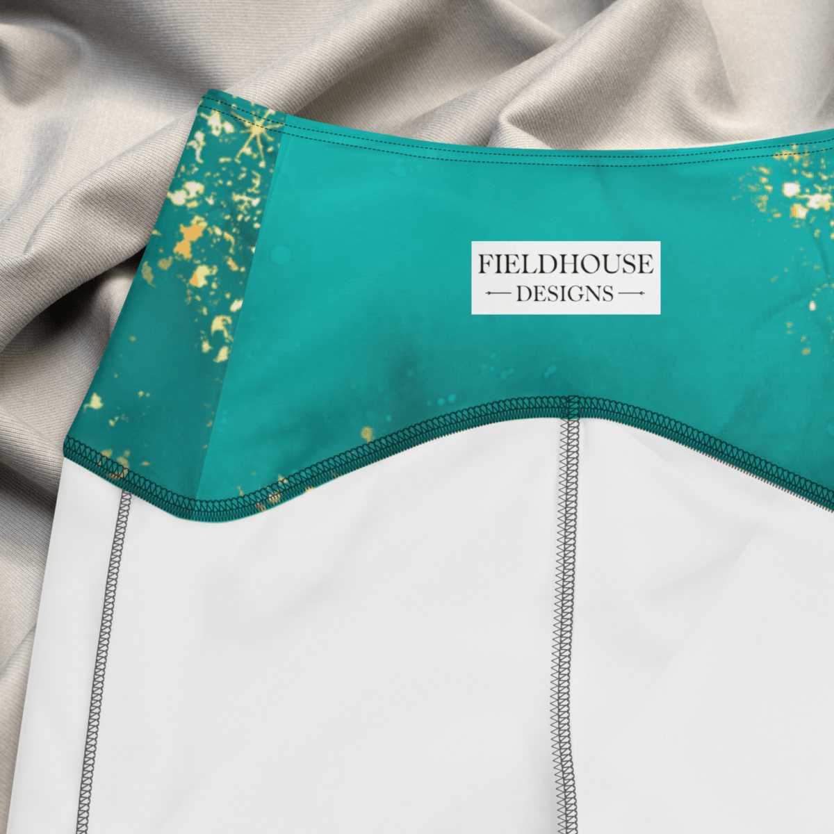 Teal waistband with gold speckles and 'Fieldhouse Designs' label on a gray fabric background