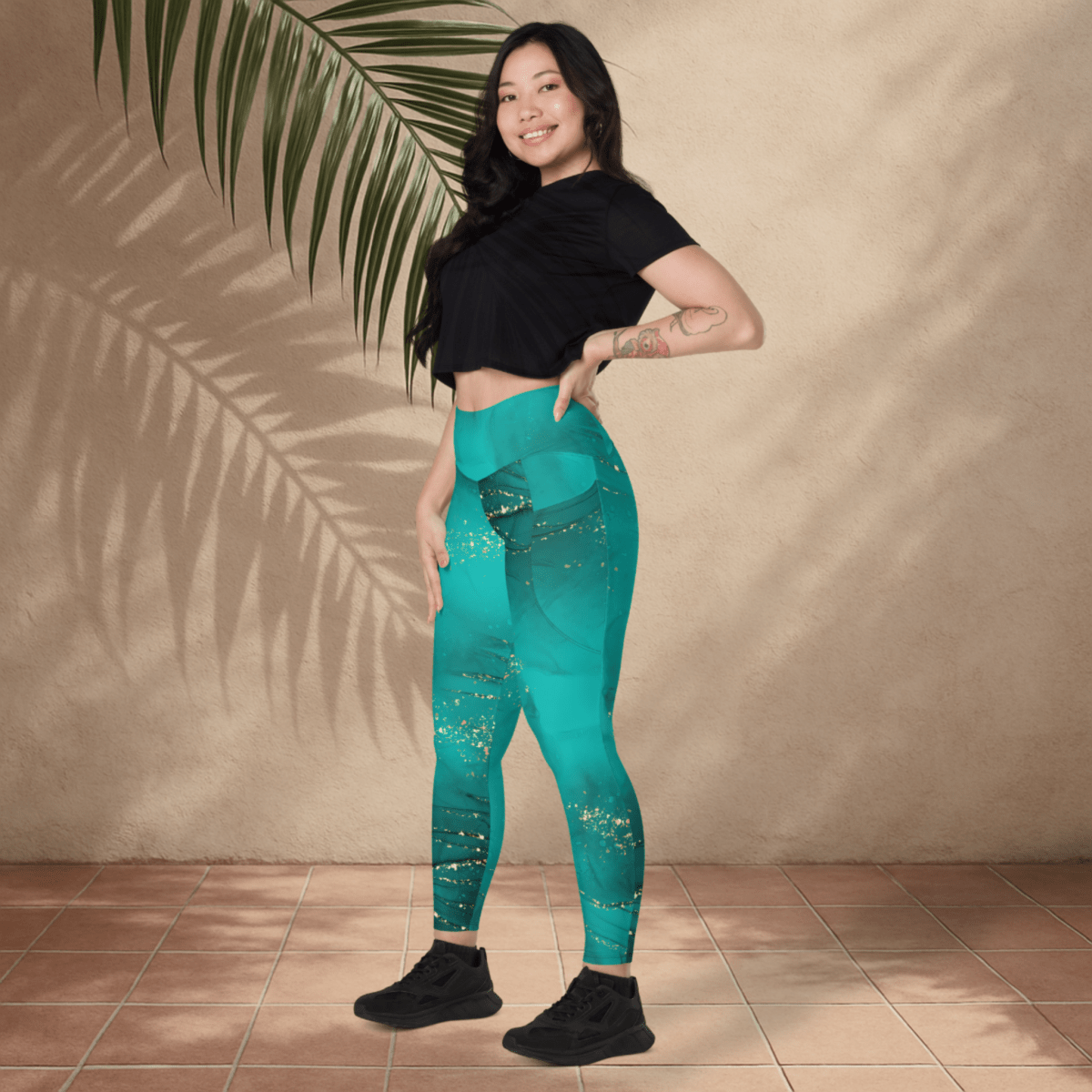 Woman wearing teal leggings with a starry pattern against a beige wall.