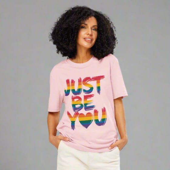 Woman wearing a pink t-shirt with 'JUST BE YOU' text on a white background