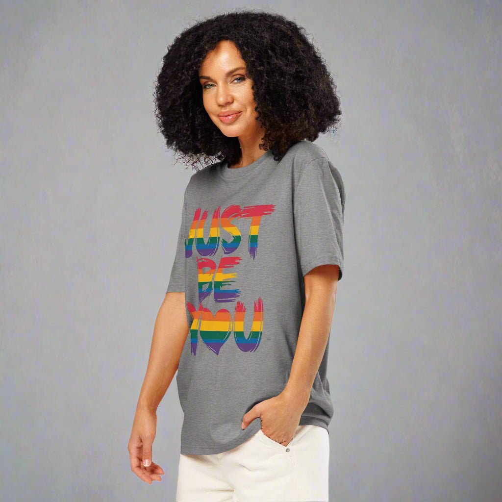 Woman wearing a gray t-shirt with 'JUST BE YOU' in rainbow colors on a white background